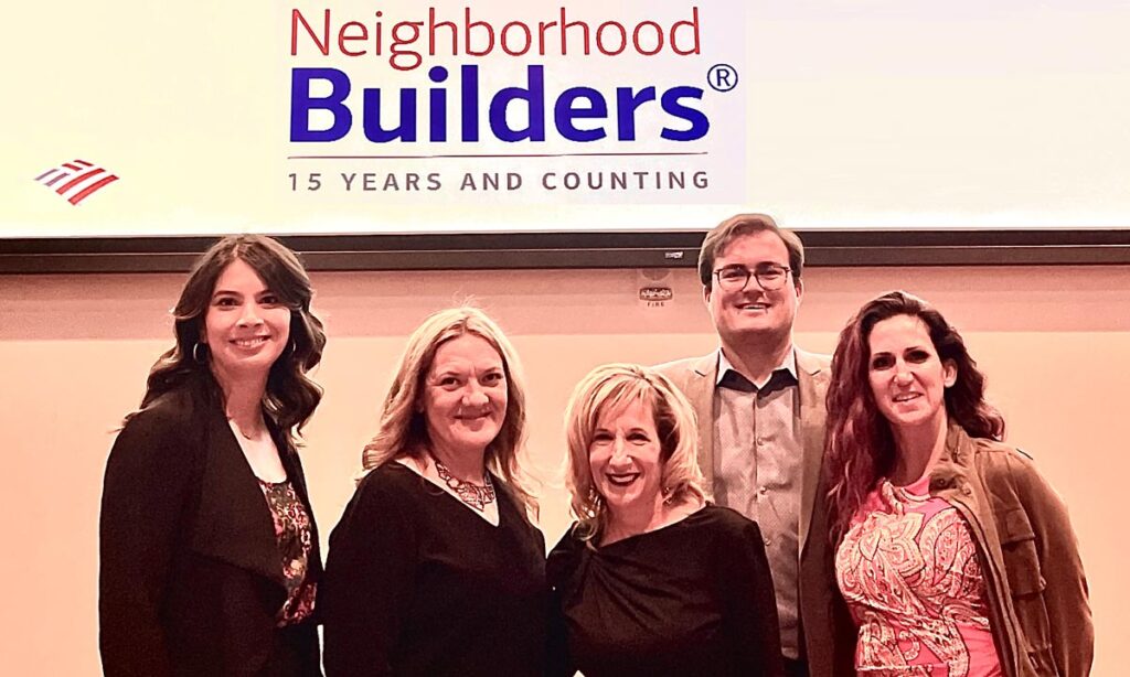 The Arouet Foundation team in front of a large projector screen that reads Neighborhood Builders