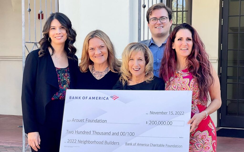 The Arouet Foundation team standing outside holding a large check for $200,000 from Bank of America