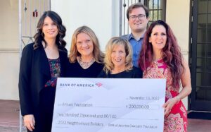 The Arouet Foundation team standing outside holding a large check for $200,000 from Bank of America